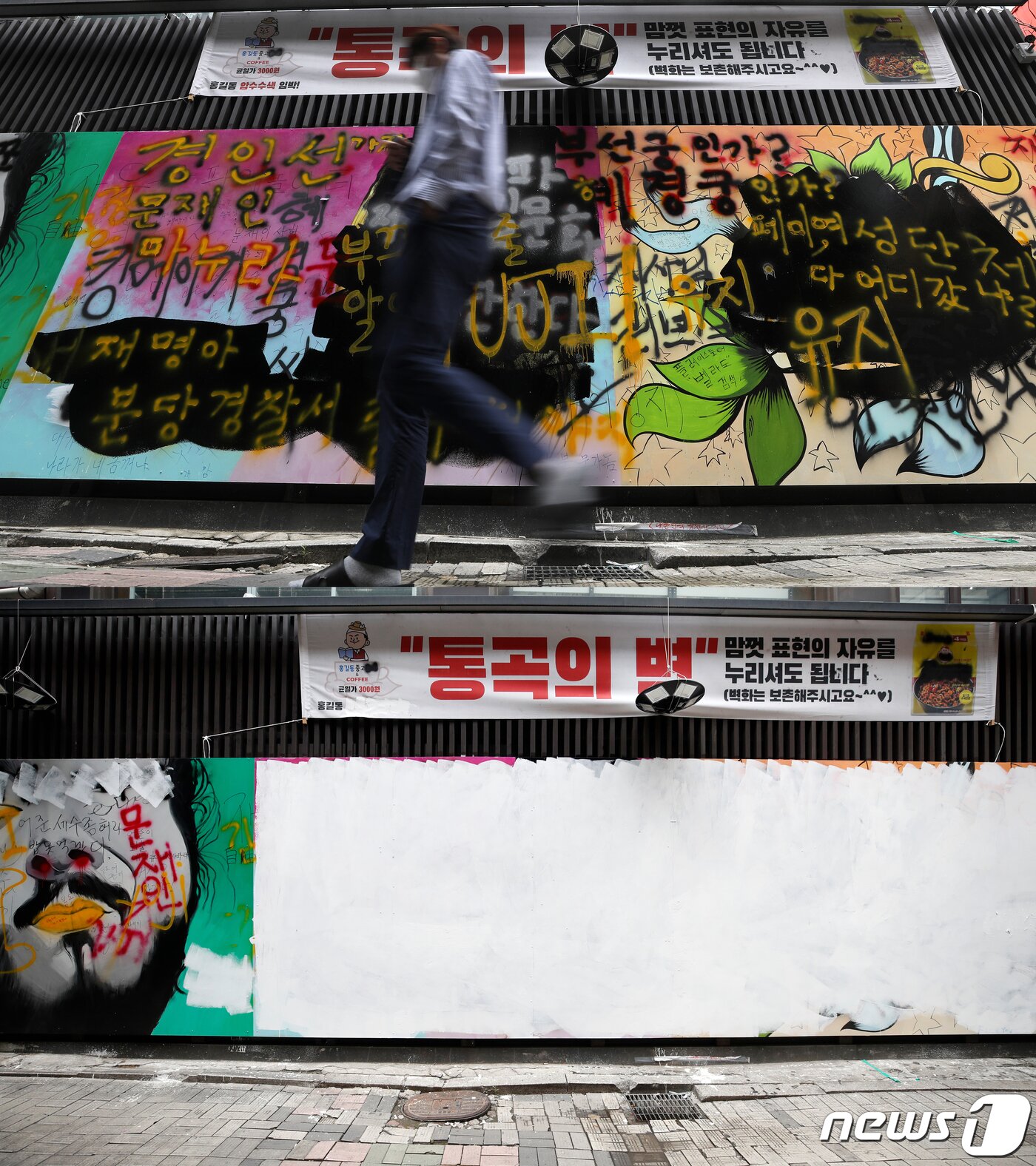 본문 이미지 - 2일 서울 종로구의 한 중고서점 외벽에 있던 윤석열 전 검찰총장 아내 김건희 씨를 비방하는 내용의 '쥴리 벽화'가 하얀 페인트로 덧칠돼 있다. (아래) 위 사진은 이날 오전 친여, 친야 성향의 지지자, 유튜버들의 낙서에 얼룩져있던 쥴리 벽화.  ⓒ News1 이승배 기자