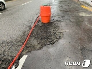 본문 이미지 - 부산 동구 범일동 한 아파트 앞에 포트홀이 생겨 도로가 통제되고 있다.(부산경찰청 제공)ⓒ 뉴스1