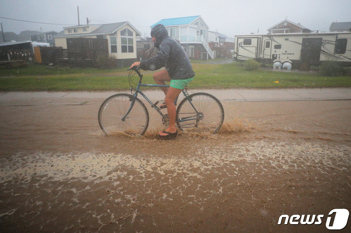 (사우스 킹스타운 로이터=뉴스1) 구진욱 기자 = 22일(현지시간) 미국 사우스 킹스타운의에서  한 시민이 허리케인 헨리로 내리는 폭우를 뚫고 자전거를 타고 있다.ⓒ 로이터=뉴스1 …