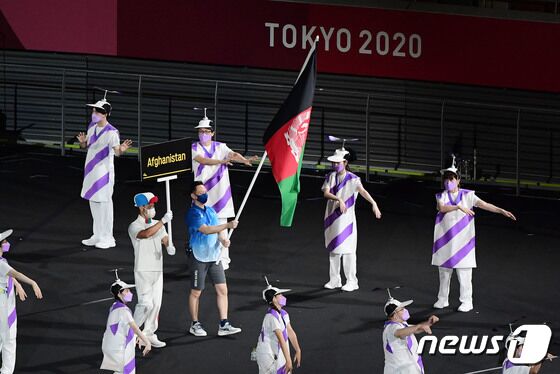 24일 오후 일본 도쿄 국립경기장(올림픽 스타디움)에서 열린 2020 도쿄 패럴림픽 개회식에서 아프가니스탄 국기가 자원봉사자의 손에 들려 입장하고 있다. 이슬람 무장단체 탈레반이 정권을 재장악한 아프가니스탄은 결국 선수단을 파견하지 못했다. 하지만 개회식 선수단 행진에 아프간 국기가 합류하며 연대의 메시지를 전 세계에 전했다. © News1 사진공동취재단
