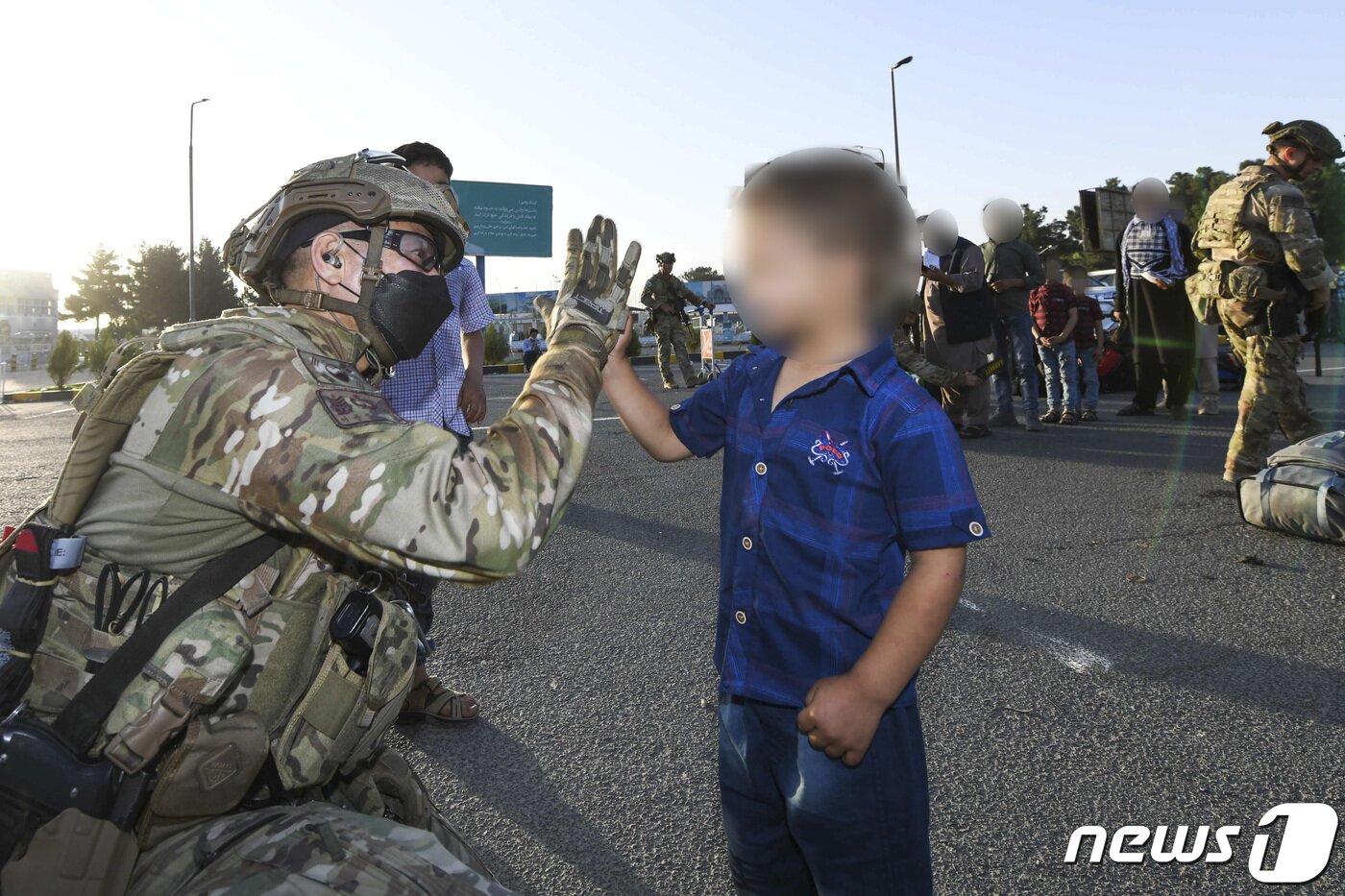 본문 이미지 - 공군 공정통제사(CCT) 요원이 25일 아프가니스탄 카불공항에서 우리나라로 갈 아프간 현지인 조력자 자녀와 손을 부딪히며 인사하고 있다. . (공군 제공) 2021.8.26/뉴스1