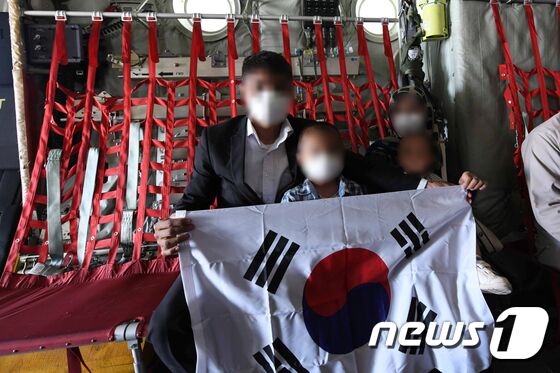 한국으로 이송될 아프가니스탄 현지 조력자 가족이 25일(현지시간) 아프가니스탄 카불공항에서 공군 C-130J 수송기에 탑승해 태극기를 펼쳐보이고 있다. © 공군 제공