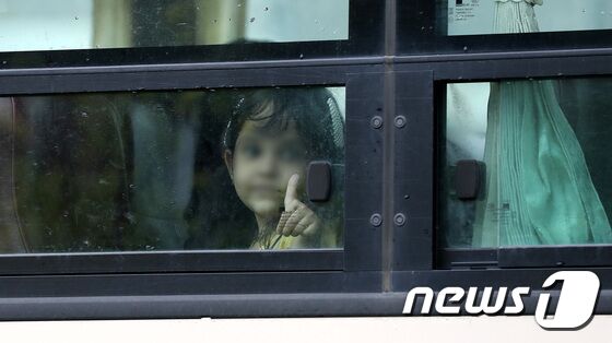 인천국제공항을 통해 입국한 아프간 인사 및 가족들이 27일 오전 임시 숙소로 지정된 경기도의 한 호텔에서 유전자증폭(PCR) 음성 판정을 받고 진천 공무원연수원으로 출발하고 있다. 한 아프간 어린이가 창밖으로 엄지척을 하고 있다. © News1 박지혜 기자