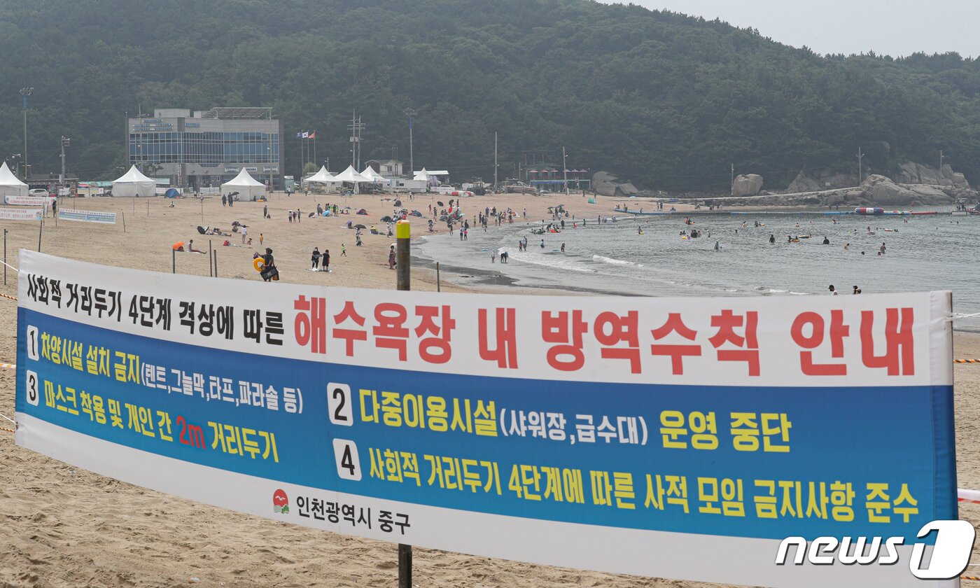 본문 이미지 - 본격적인 휴가철을 맞은 3일 오전 인천광역시 중구 을왕리해수욕장에서 거리두기 방역수칙 안내 플래카드 뒤로 피서객들이 물놀이를 즐기거나 모래사장에서 휴식을 취하고 있다. 인천시는 사회적 거리두기 4단계로 격상함에 따라 인천 중구 해수욕장을 임시폐장했다. 임시폐장한 해수욕장에서는 산책, 물놀이가 가능하지만 물놀이를 제외하고는 마스크를 착용해야 한다.  ⓒ News1 성동훈 기자