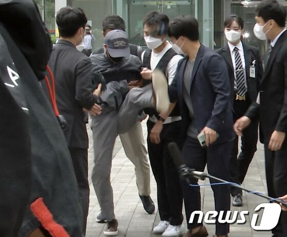 전자발찌를 훼손하고 여성 2명을 살해한 혐의를 받는 성범죄 전과자 강모씨(56)가 31일 서울 송파구 동부지법에서 구속 전 피의자 심문(영장실질심사)을 받기 위해 출석도중 취재진의 마이크를 발로 걷어차고 있다.
