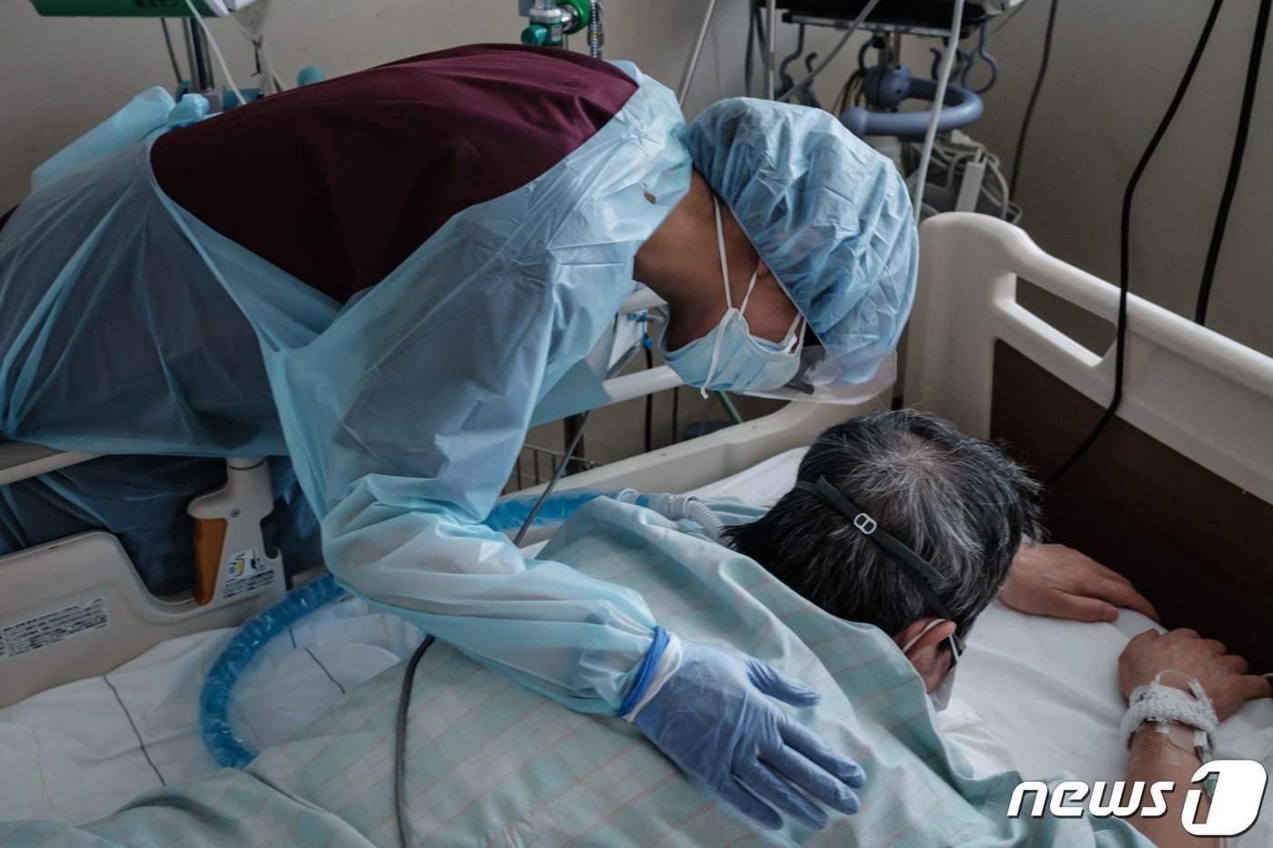 본문 이미지 - 3일 (현지시간) 일본 삿포로에 있는 홋카이도 대학병원에서 방호복을 입은 의료진이 엎드려 있는 코로나19 환자를 위로하고 있다. ⓒ AFP=뉴스1 ⓒ News1 우동명 기자
