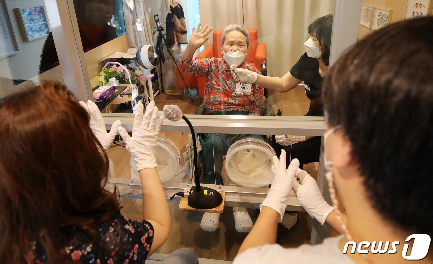 본문 이미지 - 추석 연휴를 포함해 2주간 요양병원과 요양시설 방문 면회가 허용된 13일 오후 서울 성동구 시립동부노인요양센터에 설치된 면회전용공간 '가족의 거실'에서 김귀순 할머니가 아들 한승웅씨를 비롯한 가족들과 함께 비접촉 면회를 하고 있다. 정부는 13일부터 추석 연휴를 포함해 2주간 요양병원과 요양시설 방문 면회가 허용한다고 밝혔다. 단, 접촉 면회는 환자·입소자와 면회객 모두 예방접종 완료 14일이 지났을 경우에만 가능하다. 2021.9.13/뉴스1 ⓒ News1 김진환 기자