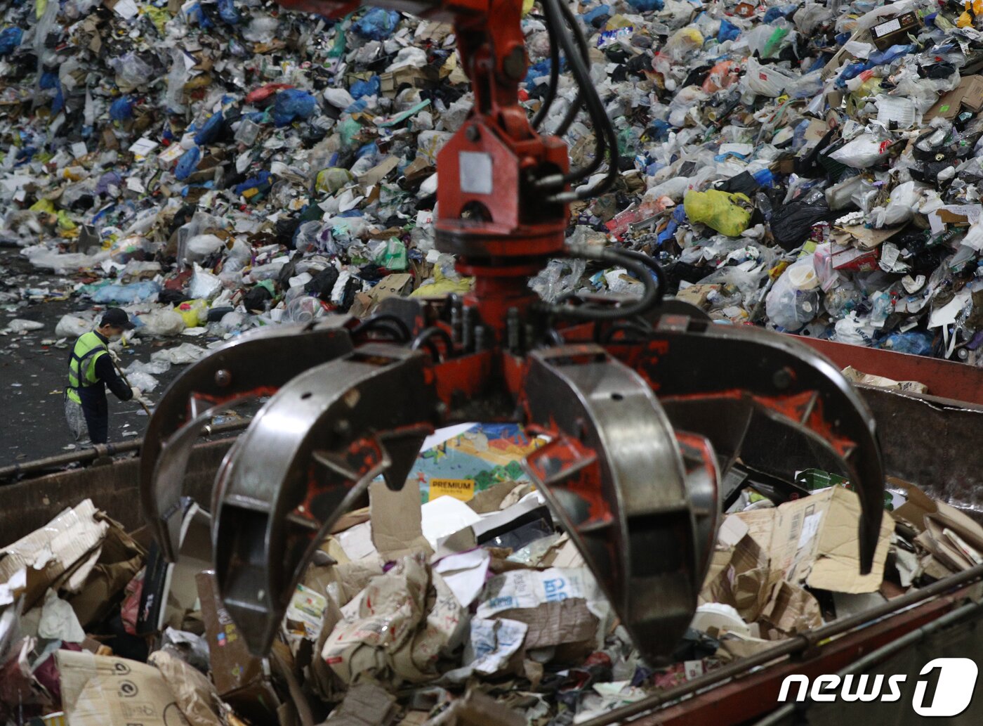 본문 이미지 - 추석 명절 연휴가 끝난 23일 서울 송파구 송파자원순환공원에서 관계자들이 재활용쓰레기 선별장에 쌓인 쓰레기를 포크레인을 이용해 분류하고 있다. 2021.9.23/뉴스1 ⓒ News1 신웅수 기자
