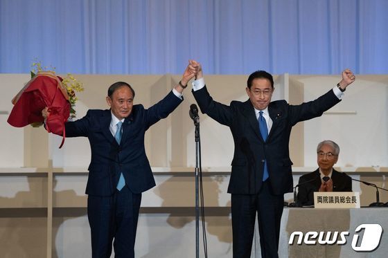 기시다 후미오 신임 자민당 총재(오른쪽)가 29일(현지시간) 도쿄에서 총재에 선출된 뒤 물러나는 스가 요시히데 총리와 손을 잡고 인사하고 있다. 기시다 총재는 내달 초 의회 선출 절차를 거쳐 총리로 정식 취임한다. AFP