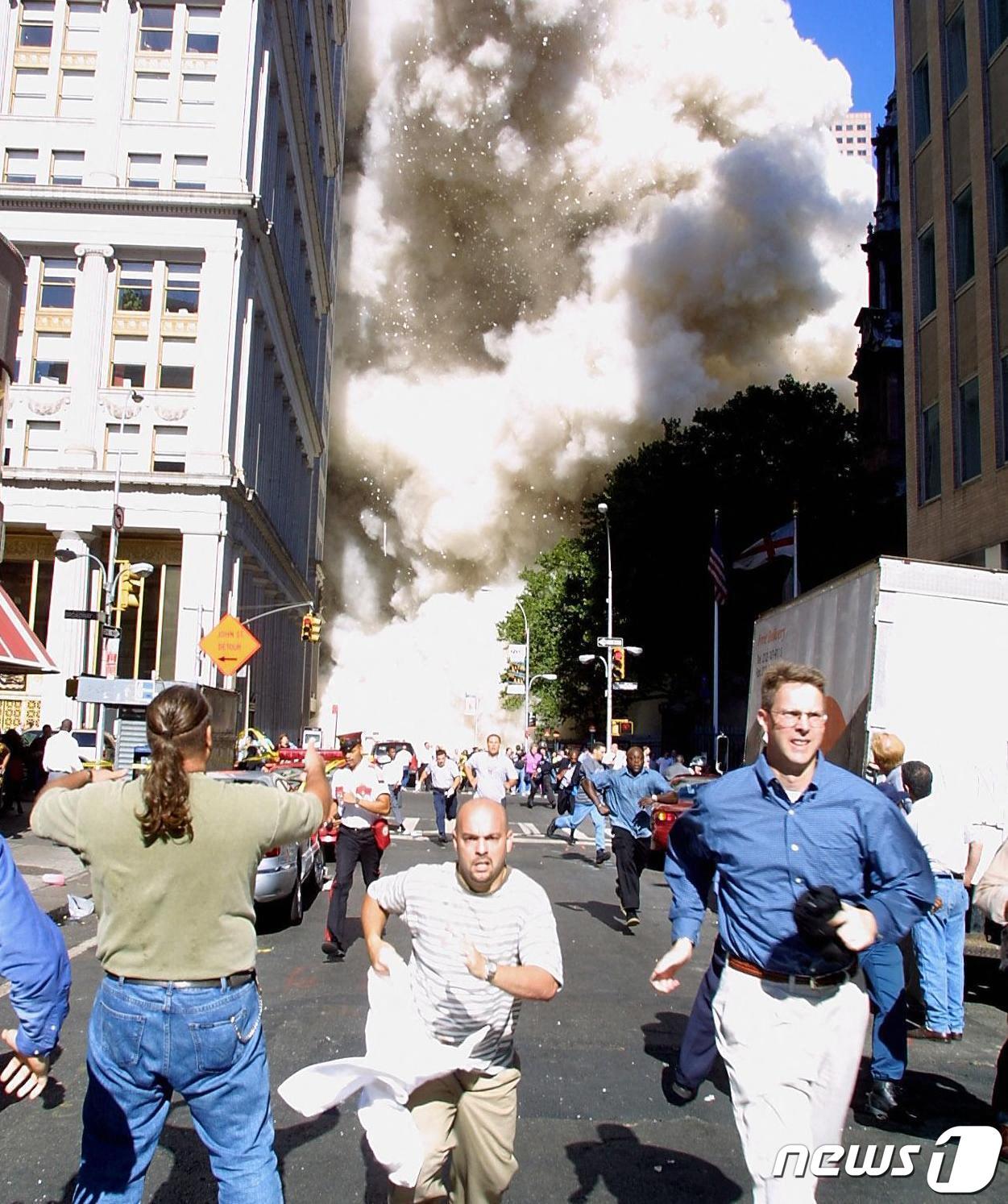 본문 이미지 - 세계무역센터 건물 인근에 있던 사람들이 사고 현장을 등지고 긴박하게 도망치고 있다. 2001.09.11 ⓒ AFP=뉴스1