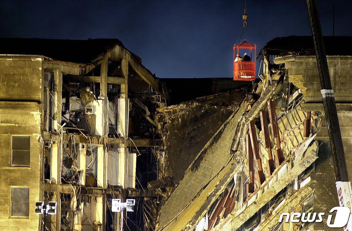 본문 이미지 - 구조대원 2명이 크레인을 타고 펜타곤 건물의 충돌 현장을 조사하고 있다. 2001.09.12 ⓒ AFP=뉴스1