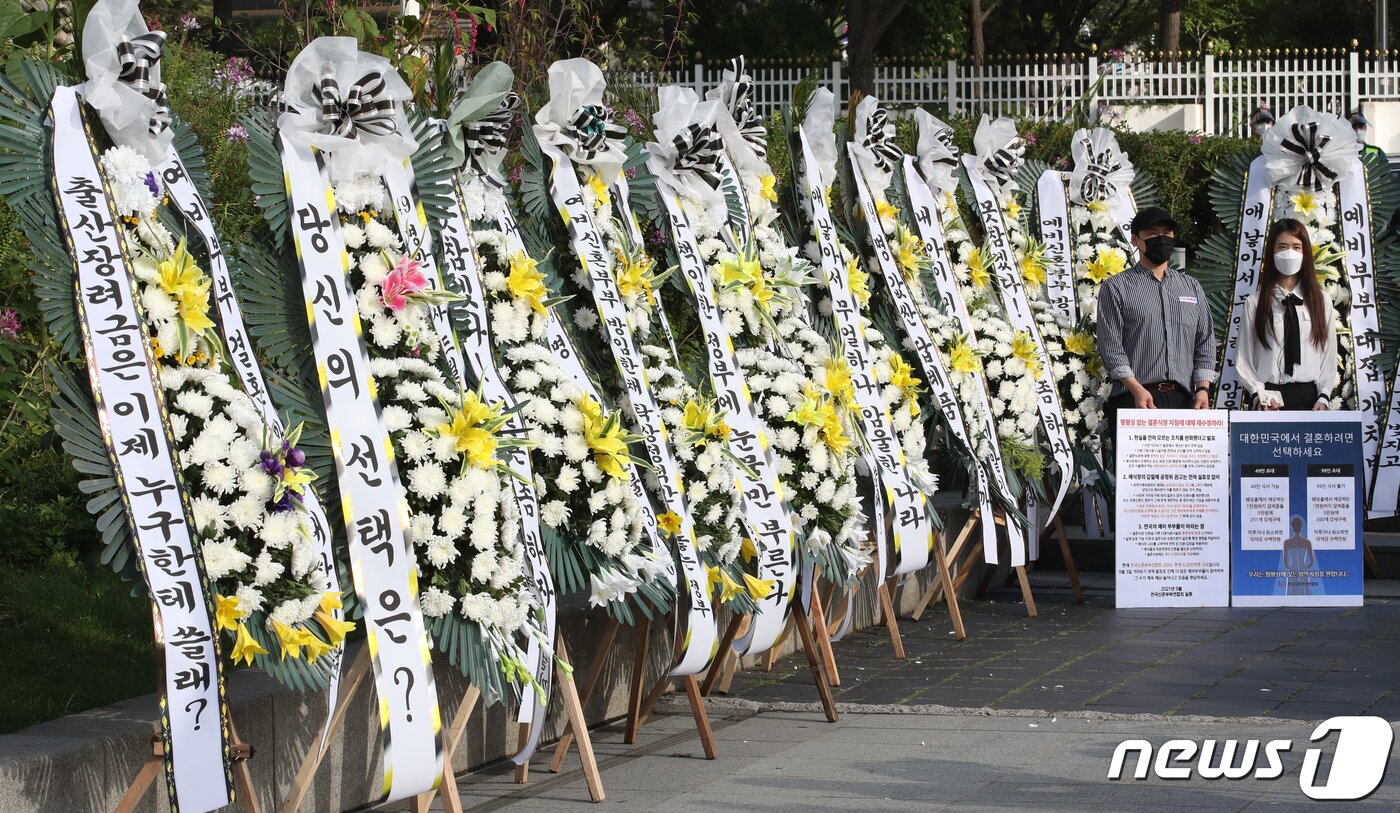 본문 이미지 - 9일 오전 서울 종로구 정부서울청사 인근에서 전국신혼부부연합회(연합회) 주최로 열린 화환시위에서 예비 신랑 신부가 정부의 방역 지침에 반발하는 문구를 들고 있다. 021.9.9/뉴스1 ⓒ News1 송원영 기자