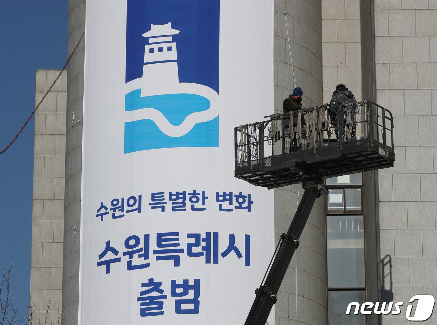 본문 이미지 - 수원·용인·고양·창원시가 특례시 출범을 하루 앞둔 12일 오후 경기도 수원시 팔달구 수원시청 외벽에 관계자들이 특례시 출범을 알리는 현수막을 설치하고 있다. 2022.1.12/뉴스1 ⓒ News1 김영운 기자