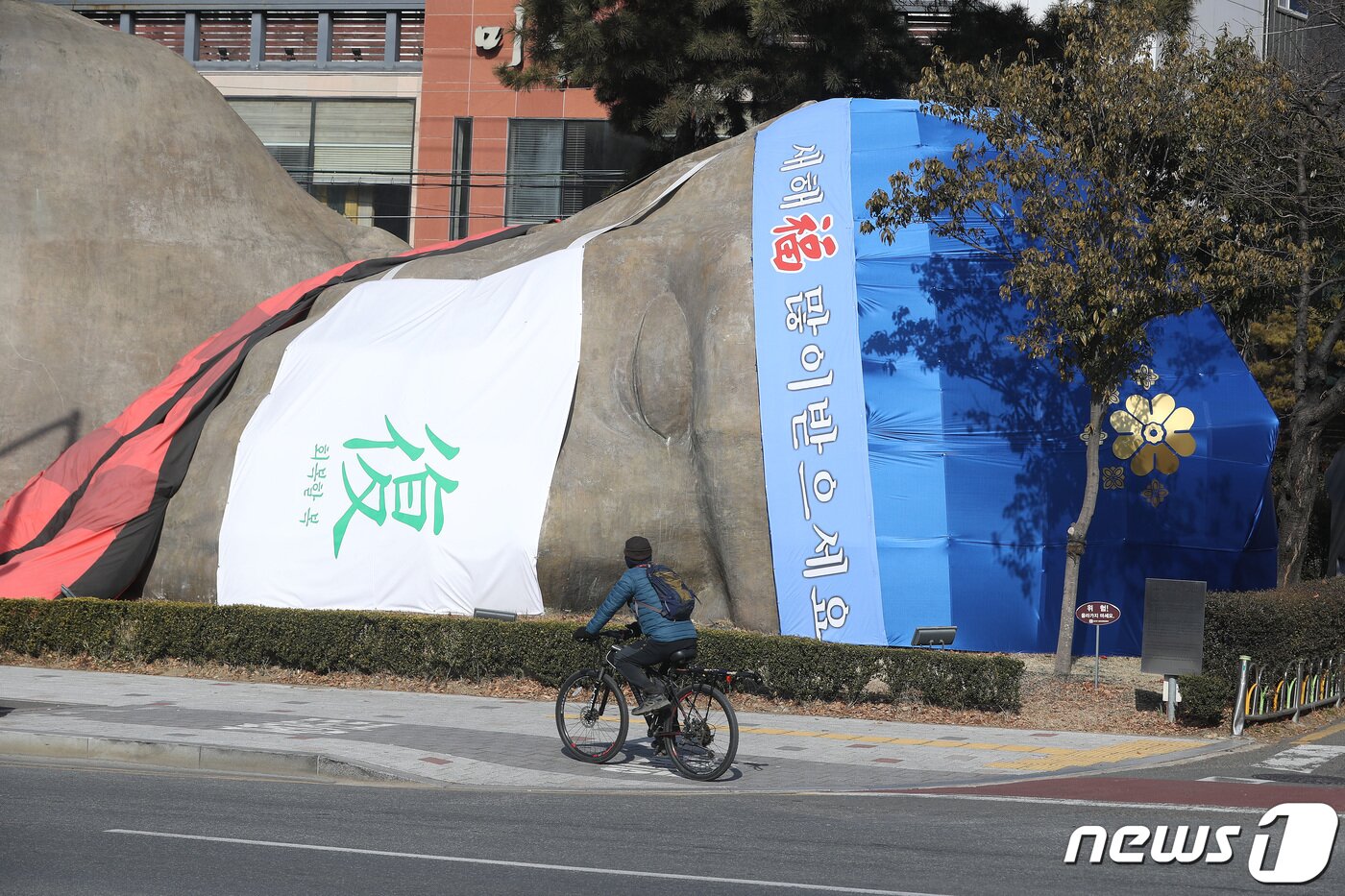 본문 이미지 - 설 명절을 앞두고 17일 오전 대구 달서구 선사시대로 랜드마크 '2만 년 역사가 잠든 곳' 원시인 조형물에 회복할 복(復) 마스크를 비롯해 새해 인사 메시지와 도령모자로 장식한 설빔이 눈길을 끌고 있다.  2022.1.17/뉴스1 ⓒ News1 공정식 기자