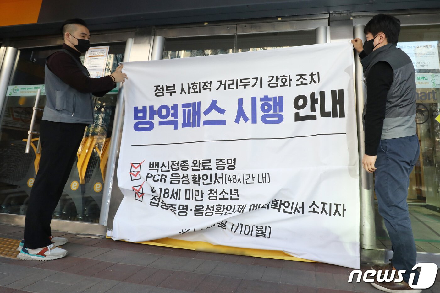 본문 이미지 - 전국 대형마트·백화점 등에 대한 방역패스(접종증명·음성확인제) 적용이 해제된 18일 오전 대구시내 한 대형마트 출입구에서 마트 관계자들이 영업 개시 전 방역패스 시행 안내 현수막을 철거하고 있다. 마트 관계자는 "정부의 방역패스 적용 해제 조치에 따라 안심콜과 QR코드 확인을 통해 코로나19 확산 방지를 위한 출입관리를 평소대로 시행한다＂고 말했다. 2022.1.18/뉴스1 ⓒ News1 공정식 기자
