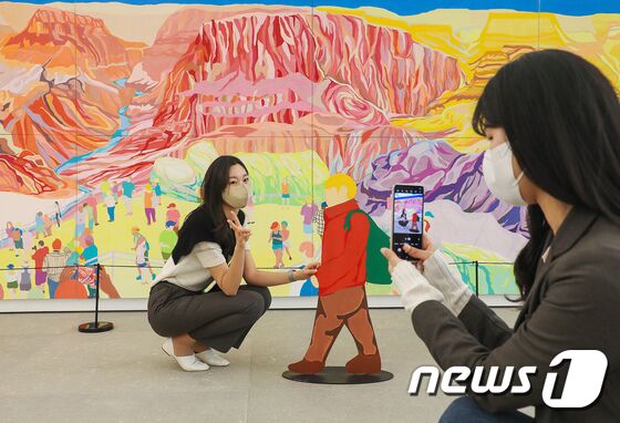 26일 오전 서울 양천구 현대백화점 목동점 7층 글라스 하우스를 찾은 시민들이 기념촬영을 하고 있다. 현대백화점은 다음달 9일까지 목동점 7층 실내·외 조경 공간 '글라스 하우스'에서 여행을 주제로한 회화 전시 '일상으로부터의 탈출(Escape From Trivia)'을 진행한다. 이번 전시에서는 해외 유명 관광지들의 모습을 담은 작품 30여 점을 선보인다. (현대백화점 제공) 2022.1.26/뉴스1