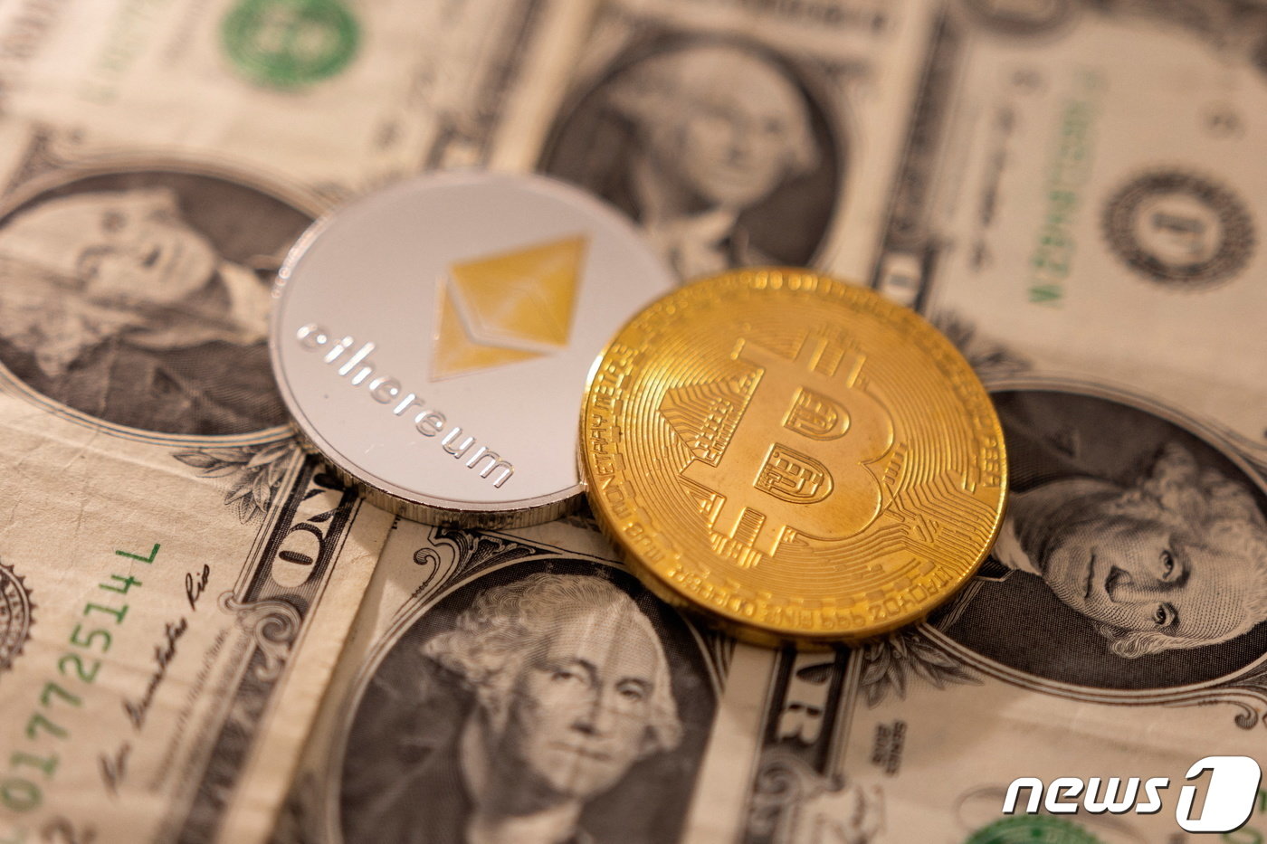본문 이미지 - 암호화폐 이더리움(왼쪽)과 비트코인이 미국 달러 위에 놓여 있다. ⓒ 로이터=뉴스1 ⓒ News1 김지현 기자