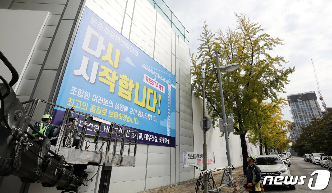 본문 이미지 - 16일 서울 강동구 둔촌주공 재건축 현장에서 관계자들이 공사 재개를 알리는 현수막을 붙이고 있다. 6개월간 멈춰섰던 둔촌주공아파트 재건축 사업이 오는 17일부터 다시 시작된다. 2022.10.16/뉴스1 ⓒ News1 박지혜 기자