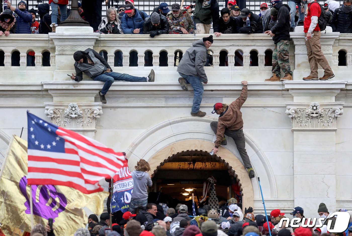본문 이미지 - 2021년 1월 도널드 트럼프 당시 대통령 지지자들이 당시 조 바이든 대통령 당선인 인준 절차가 진행되던 워싱턴 DC 국회의사당 안으로 들어가기 위해 벽을 타고 난입한 모습.  2021.01.06 ⓒ 로이터=뉴스1 ⓒ News1 권진영 기자