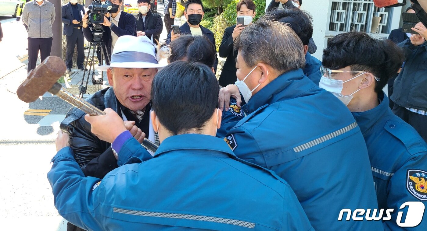 본문 이미지 - 오천도 애국국민운동대연합 대표가 25일 충북 청주시청 앞에서 본관동 철거를 주장하며 망치를 들고 청주시청에 진입하려다 청원경찰에 제지당하고 있다.2022.10.25/ⓒ 뉴스1 강준식 기자