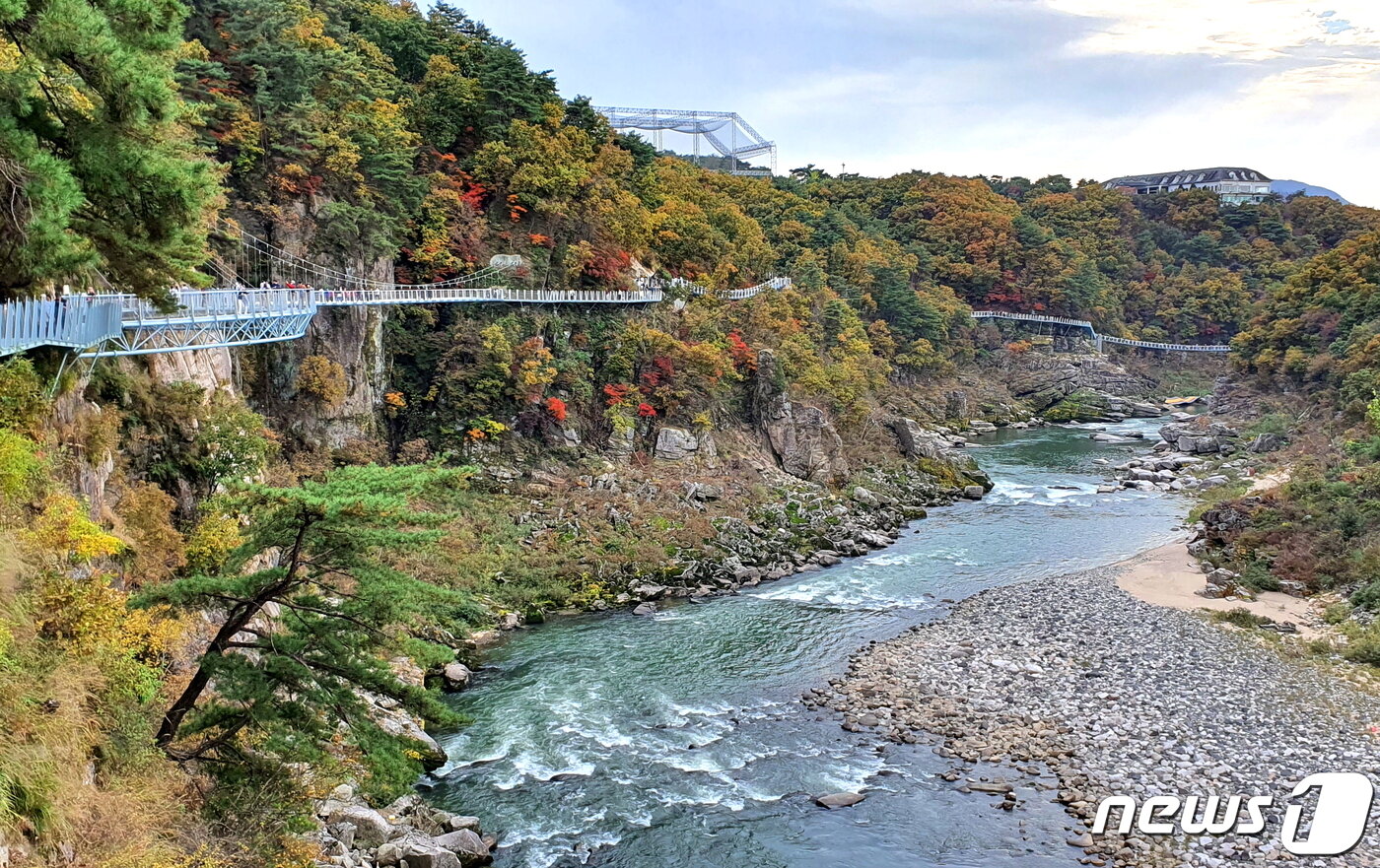 본문 이미지 - 한탄강 풍경. 큰 여울(漢灘)에서 물보라를 일으키며 흘러가는 한탄강. 왼쪽의 현무암 절벽에 설치된 3.6km의 잔도로 사람들이 걷고 있다.