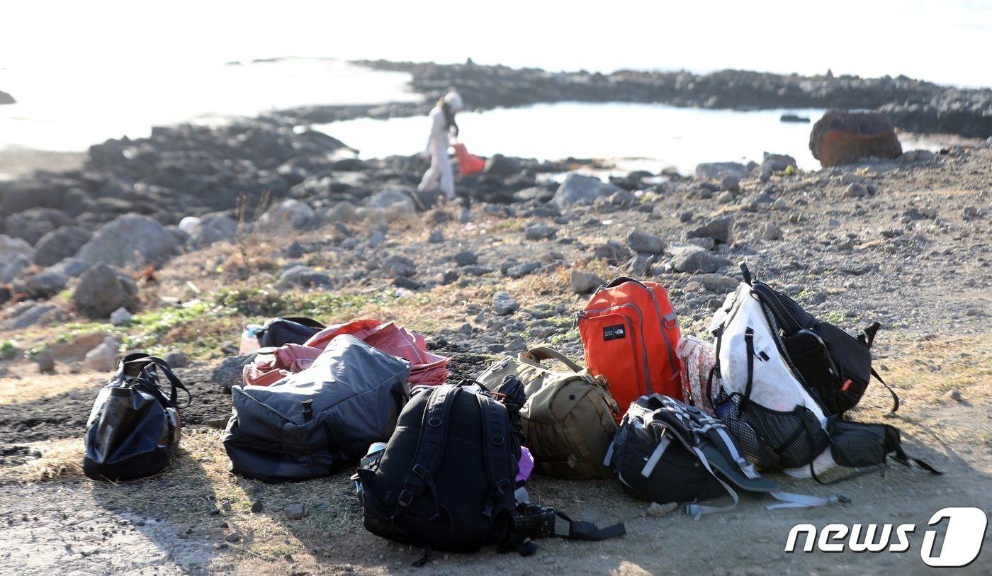 본문 이미지 - 우도 제로웨이스트 여행 참가자들이 배낭을 벗어놓고 해안가 쓰레기를 줍고 있다ⓒ News1 고동명 기자