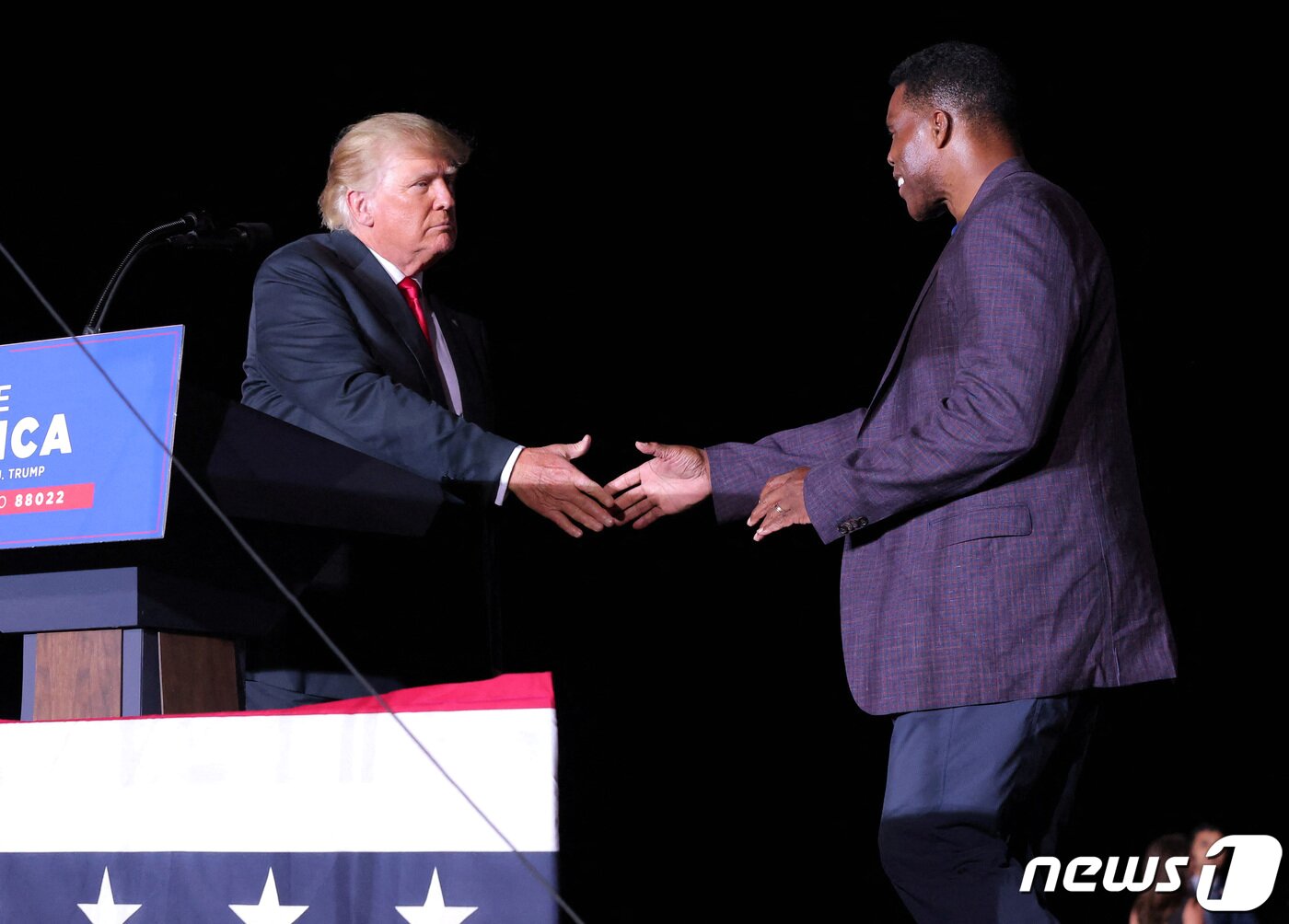 본문 이미지 - 도널드 트럼프 전 미국 대통령이 2021년 9월25일(현지시간) 미국 조지아주에서 열린 집회 도중 전직 미국프로풋볼(NFL) 스타 출신인 허셜 워커 상원의원 후보와 악수를 나누고 있는 모습. ⓒ 로이터=뉴스1 ⓒ News1 김현 특파원