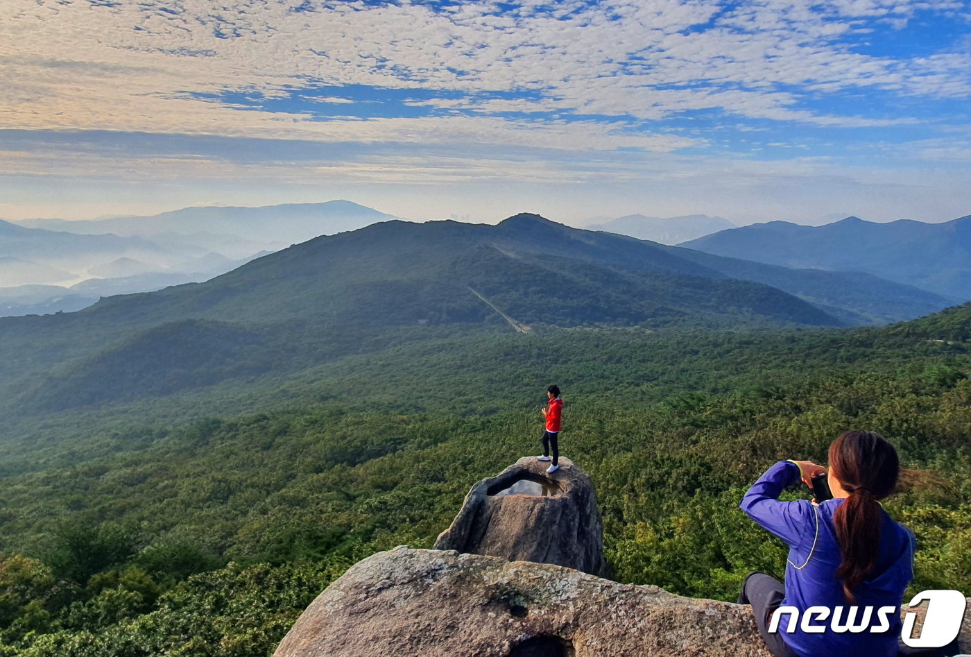 본문 이미지 - 금샘 풍경. 한 커플이 인생 샷을 찍고 있다. 여기서 바라보는 금정산이 널찍하고 유순하다