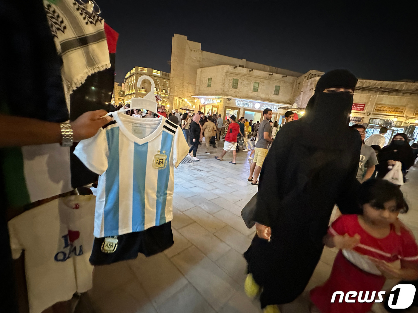 (도하 로이터=뉴스1) 김성식 기자 = 6일(현지시간) 월드컵을 한 달여 앞둔 카타르 도하에서 한 노점상이 아이와 함께 지나가는 여성에게 아르헨티나 축구 국가대표팀 유니폼을 사라고 …