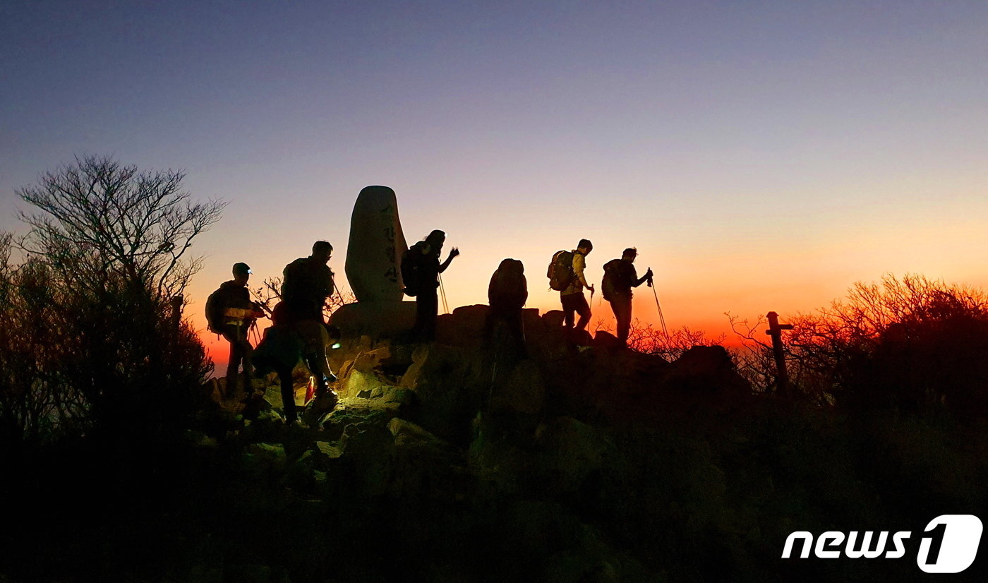 본문 이미지 - 간월산 정상의 새벽. 지평선의 끝에 새벽빛이 찬연한 가운데, 정상석을 통과하는 사람들.