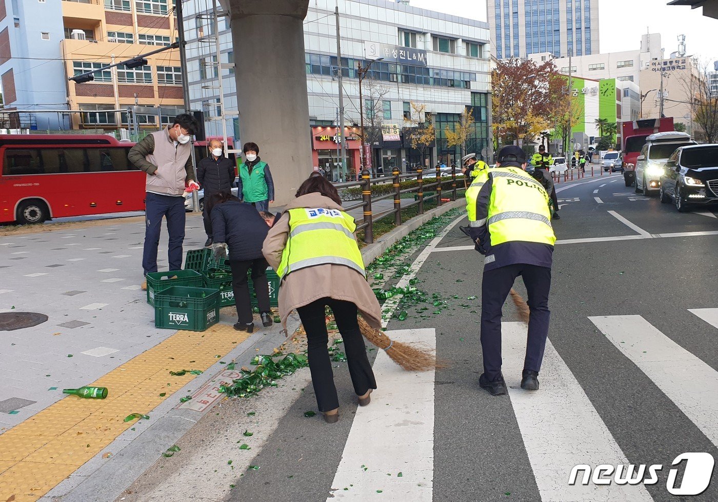 본문 이미지 - 수능 시험장인 연제구 이사벨고 정문 앞을 지나던 화물차에서 술병이 쏟아져 관계자들이 도로에 흩어진 유리조각을 정리하고 있다.(부산경찰청 제공) 