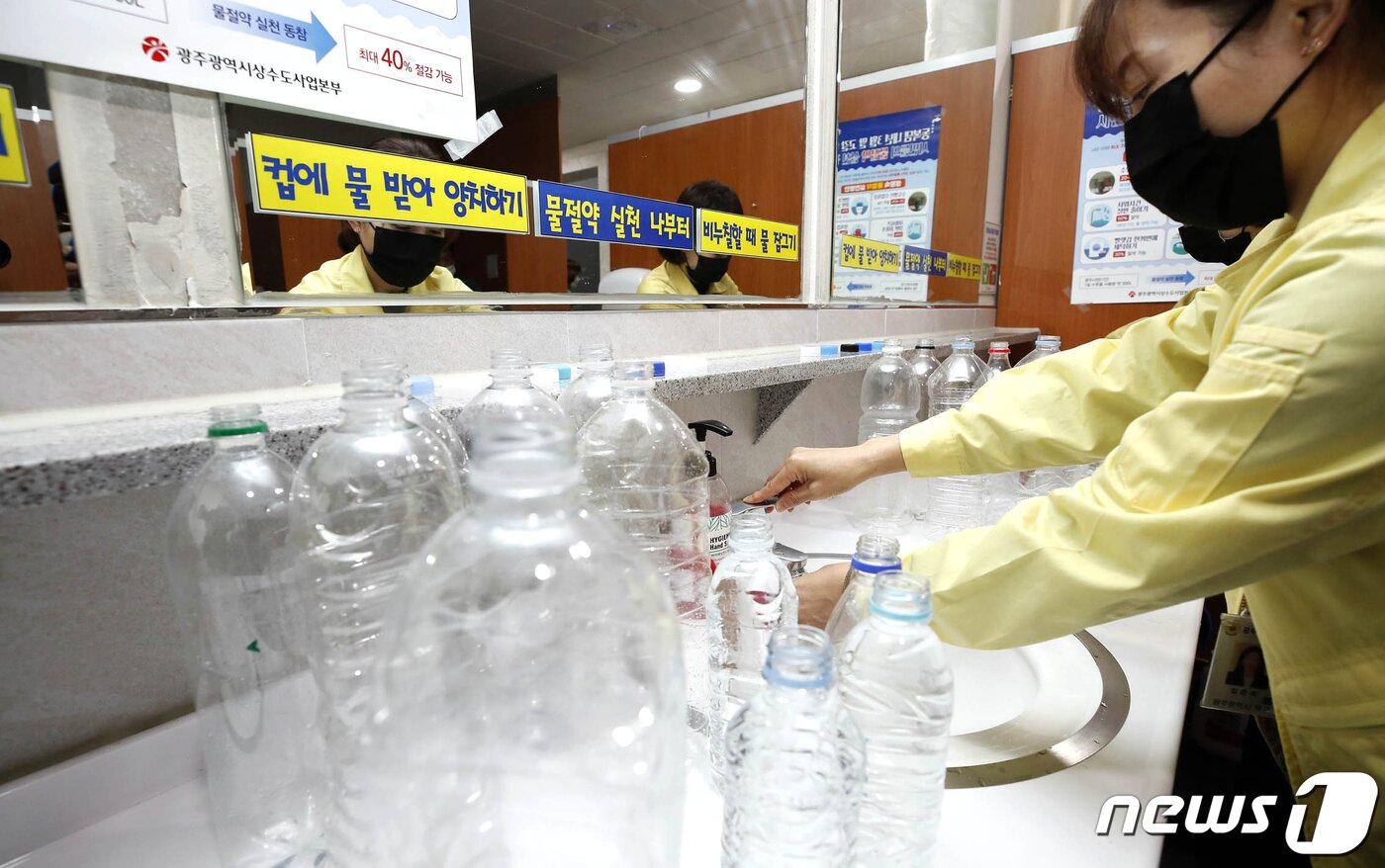본문 이미지 - 광주 북구청 화장실에서 기후환경과 직원들이 물절약 일환으로 양변기 수조에 넣을 페트병에 물을 채우고 있다.(북구 제공)/뉴스1 DB