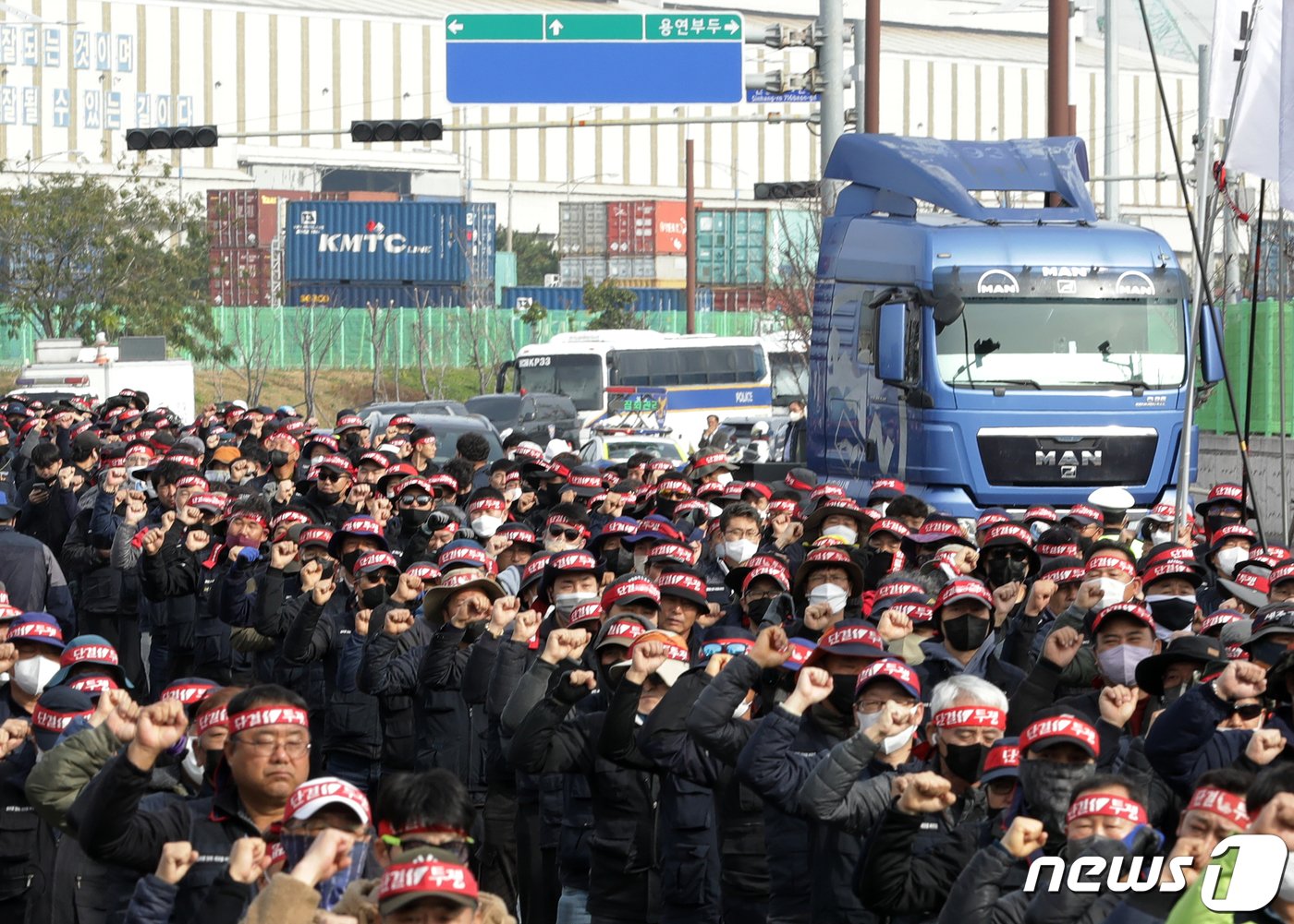 24일 울산 남구 울산신항 앞에서 민주노총 전국공공운수노동조합 화물연대 울산본부 총파업 출정식이 열린 가운데 구호를 외치는 조합원들 뒤로 화물차가 지나가고 있다. 2022.11.24/뉴스1 ⓒ News1 윤일지 기자