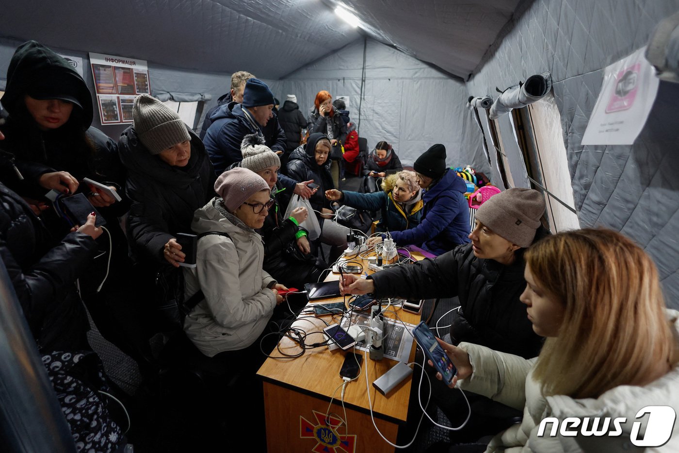본문 이미지 - 24일(현지시간) 러시아군이 우크라이나의 에너지 인프라를 집중 공격하며 우크라이나 전역이 정전된 가운데 지역 주민들이 핸드폰 충전을 위해 모여든 모습. 22.11.24 ⓒ 로이터=뉴스1 ⓒ News1 김예슬 기자