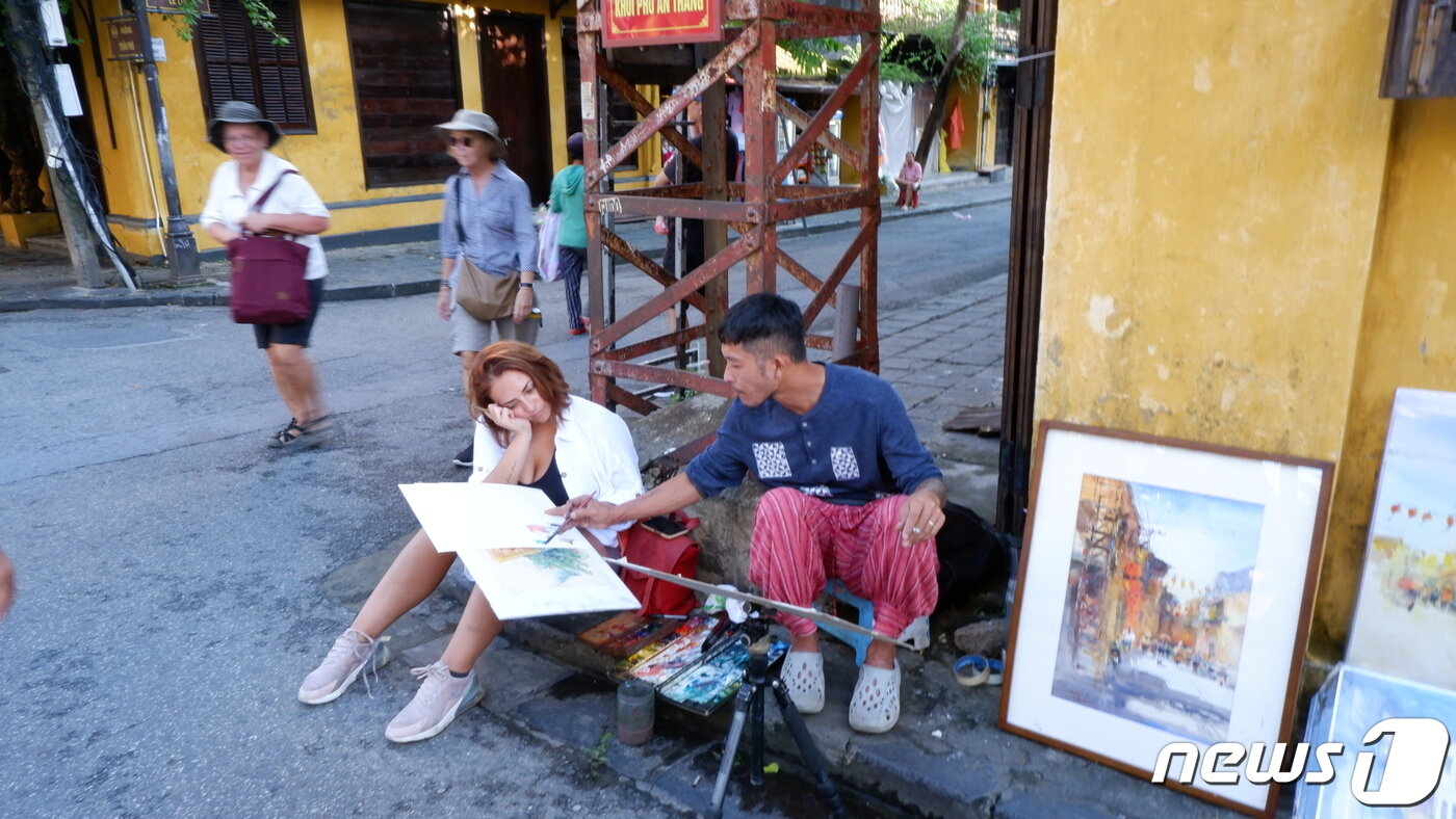 본문 이미지 - 거리 예술가와 외국인 여행객이 함께 그림을 그리고 있는 모습ⓒ News1 윤슬빈 기자