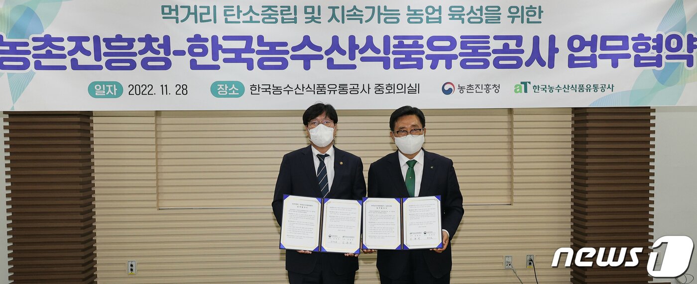 본문 이미지 - 조재호 농촌진흥청장(왼쪽)과 김춘진 한국농수산식품유통공사 사장이 28일 전남 나주혁신도시 한국농수산식품유통공사에서 먹거리 탄소중립 및 지속 가능 농업 육성을 위한 업무협약을 체결하고 있다. (농촌진흥청 제공) 2022.11.28/뉴스1