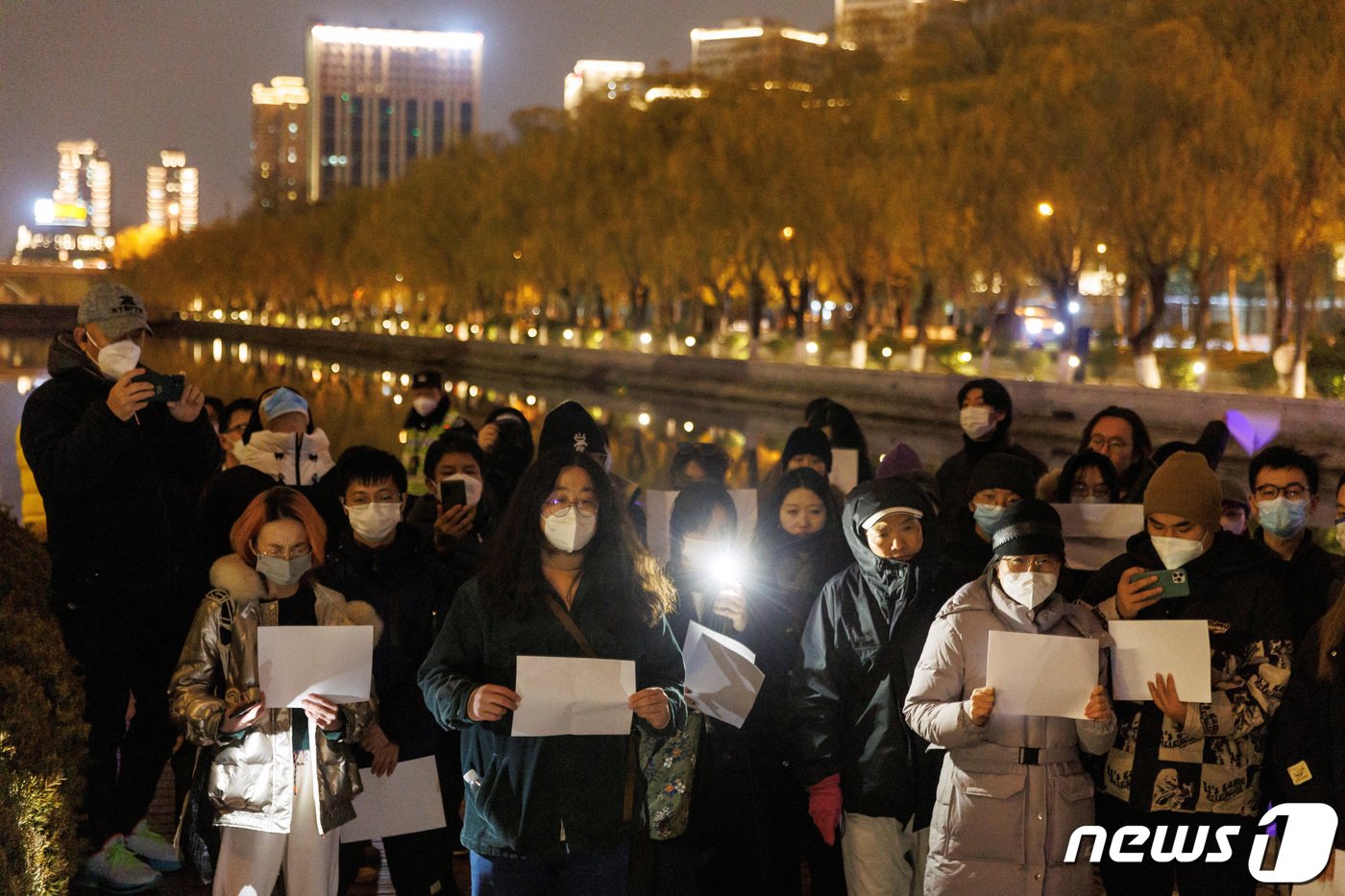 본문 이미지 - 지난 27일 중국 베이징에서 열린 우루무치 화재 희생사 추모 행사에서 사람들이 정부의 코로나19 규제에 항의하기 위해 모여 흰 종이를 들고 있다. 2022.11.28 ⓒ 로이터=뉴스1 ⓒ News1 김정률 기자