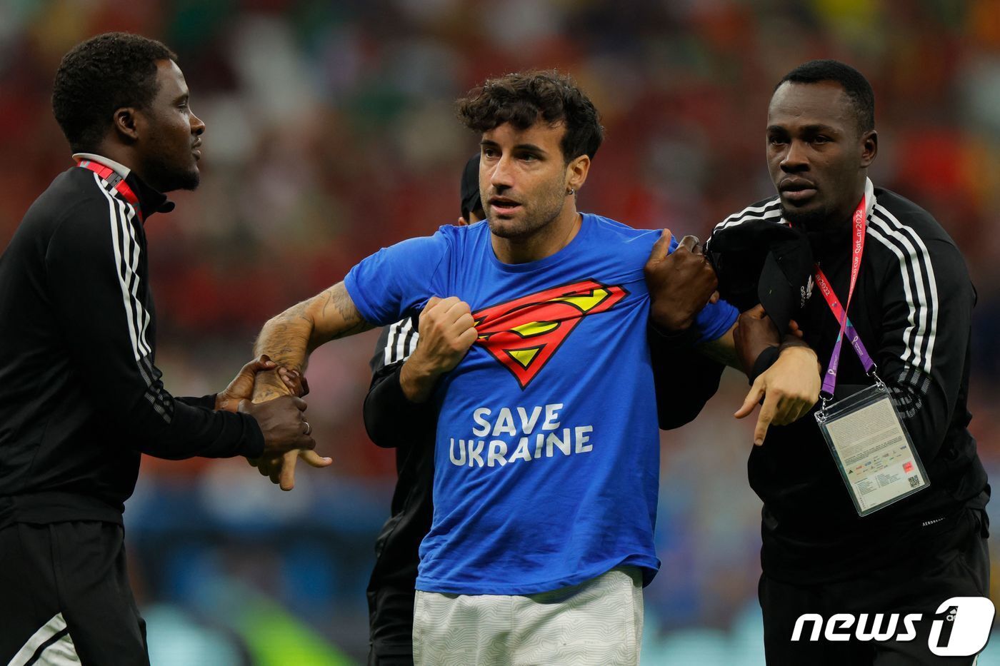 본문 이미지 - 29일(한국시간) 열린 2022 카타르 월드컵 포르투갈-우루과이전 경기 도중 그라운드에 난입한 남성이 보안 요원들에 의해 끌려나가고 있다. ⓒ AFP=뉴스1