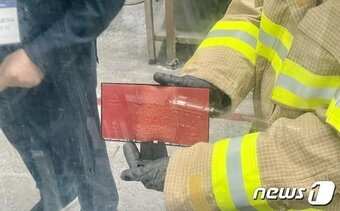 본문 이미지 - 시연자가 불이 꺼진 뒤 자동소화 패드 아랫면을 보여주고 있다. ⓒ News1 이민주 기자