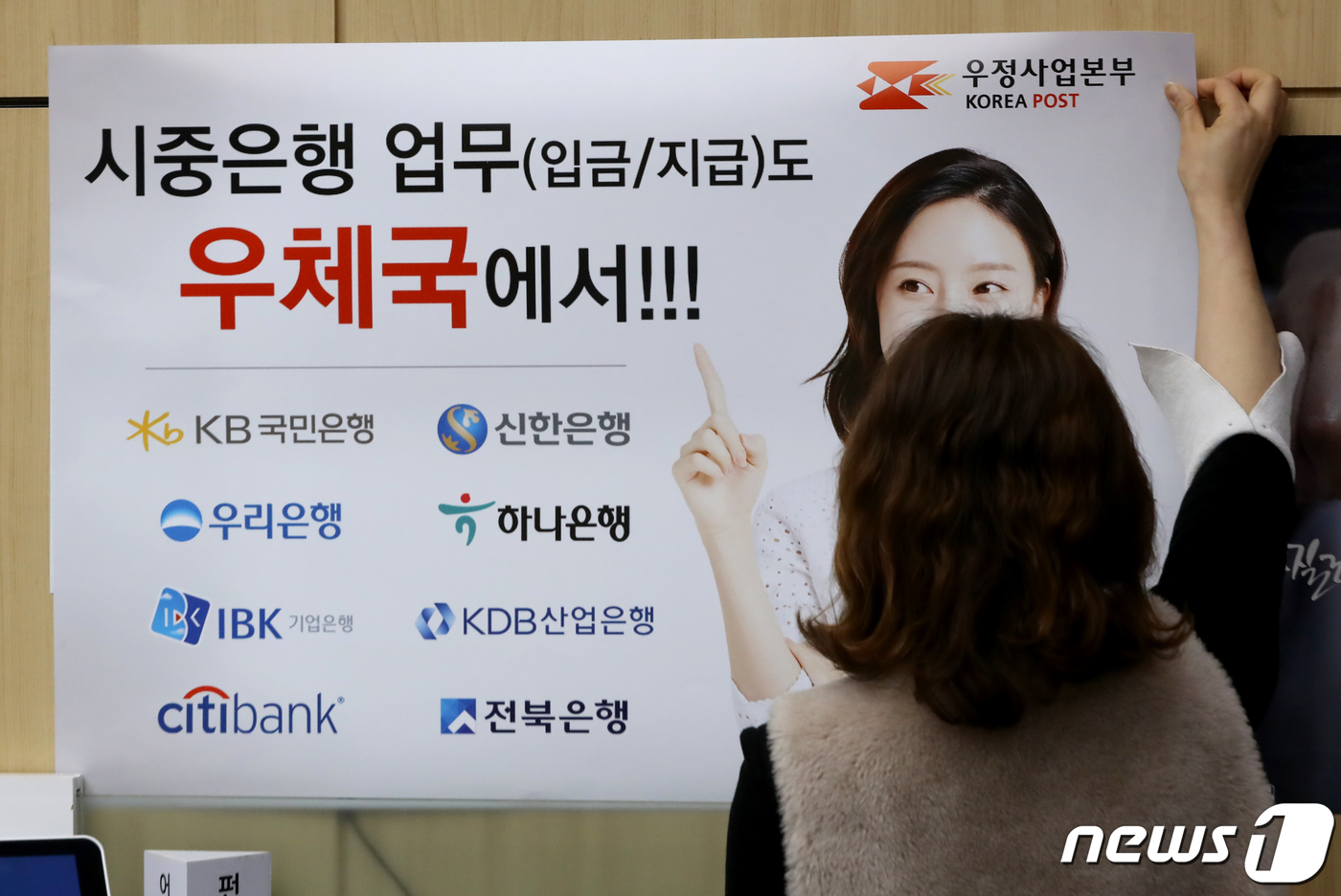(서울=뉴스1) 장수영 기자 = 30일 서울 중구 서울중앙우체국 창구에서 직원이 시중은행 입·출금 업무 안내 홍보물을 부착하고 있다.우정사업본부는 오늘부터 별도의 수수료 없이 국민 …