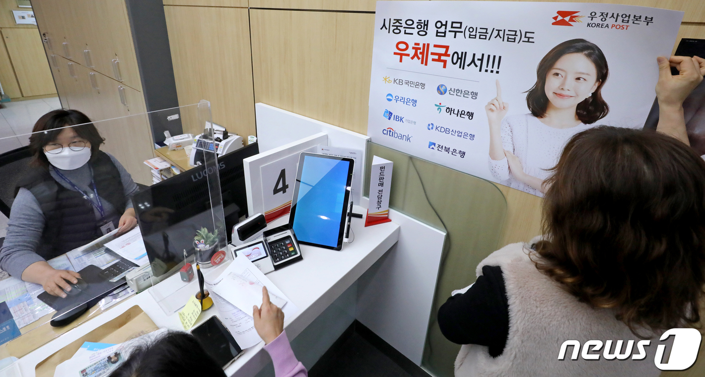 (서울=뉴스1) 장수영 기자 = 30일 서울 중구 서울중앙우체국 창구에서 직원이 시중은행 입·출금 업무 안내 홍보물을 부착하고 있다.우정사업본부는 오늘부터 별도의 수수료 없이 국민 …