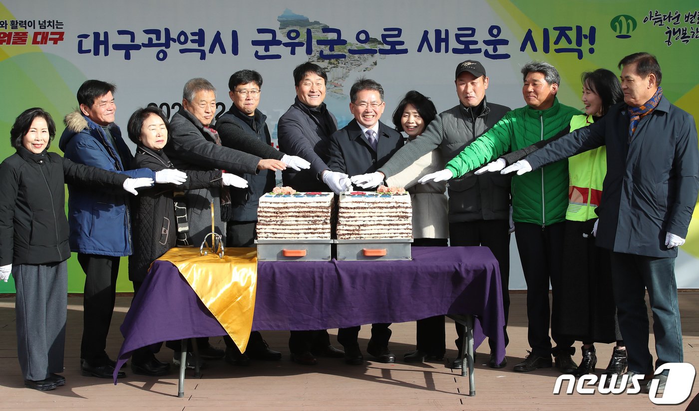 김진열 군위군수&#40;왼쪽 일곱 번째&#41;가 13일 오전 경북 군위군 군위전통시장에서 열린 &#39;대구편입법 국회통과 기념 군민 한마당&#39; 행사에 참석해 군의원을 비롯한 내빈과 함께 축하 떡을 자르고 있다. 2022.12.13/뉴스1 ⓒ News1 공정식 기자