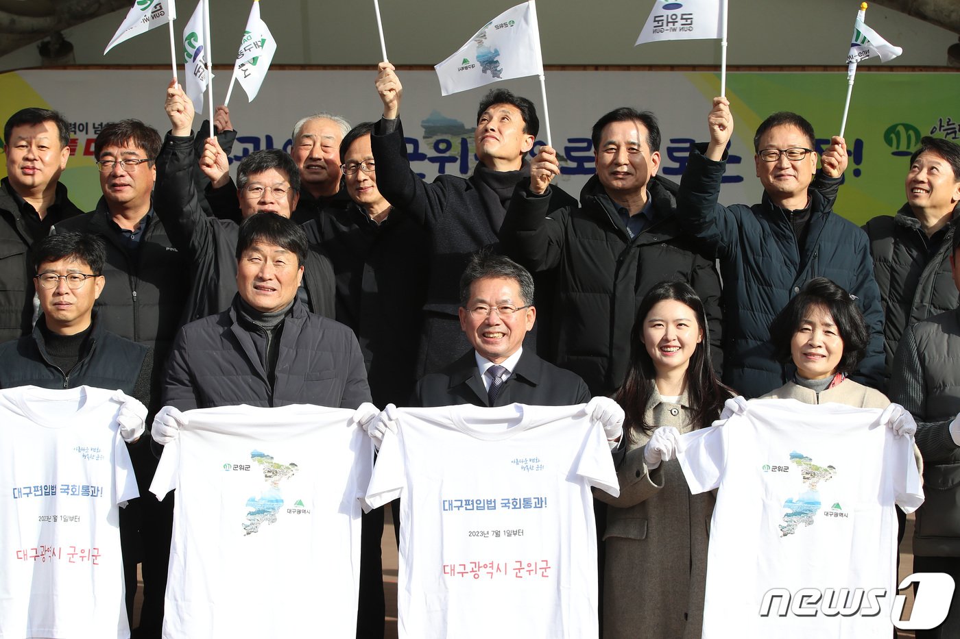 김진열 군위군수&#40;앞줄 가운데&#41;가 13일 오전 경북 군위군 군위전통시장에서 열린 &#39;대구편입법 국회통과 기념 군민 한마당&#39; 행사에 참석해 군의원을 비롯한 내빈과 함께 축하 티셔츠를 들어 보이며 기념 촬영을 하고 있다. 2022.12.13/뉴스1 ⓒ News1 공정식 기자