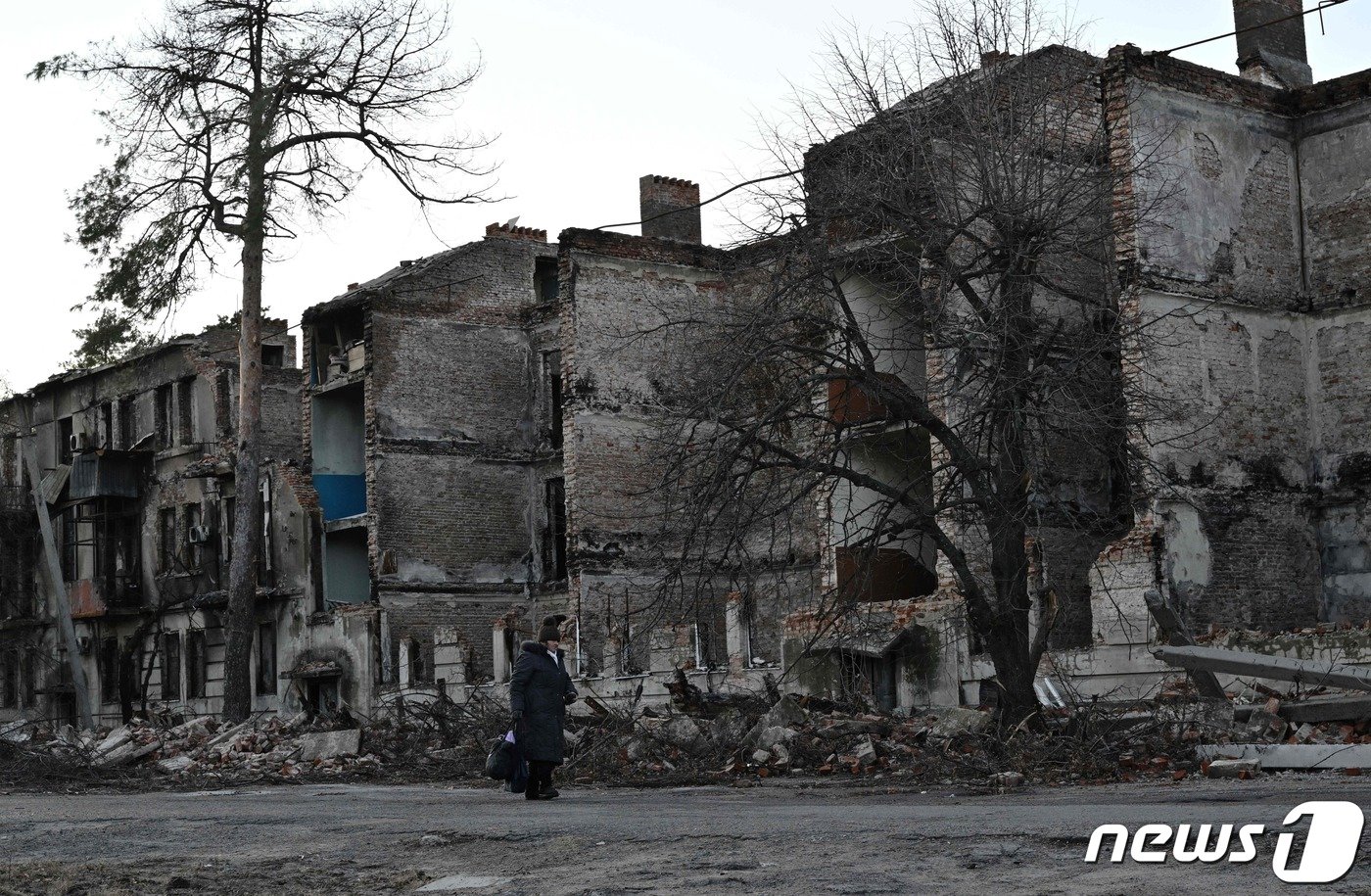 본문 이미지 - 14일&#40;현지시간&#41; 우크라이나 동부 도네츠크주&#40;州&#41; 리만에서 한 지역 주민이 러시아군의 폭격에 폐허로 변한 아파트 앞을 걸어가고 있다. ⓒ AFP=뉴스1 ⓒ News1 김성식 기자