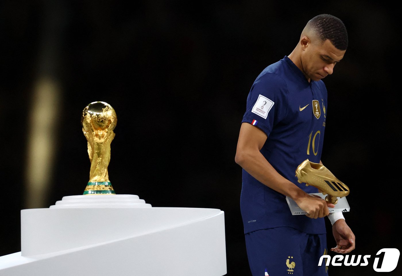 본문 이미지 - 18일(현지시간) 카타르 루사일 스타디움에서 열린 2022 국제축구연맹(FIFA) 카타르 월드컵 결승전, 아르헨티나를 상대로 패배한 프랑스의 킬리안 음바페가 대회 득점왕인 골든부트를 수상한 뒤 월드컵 트로피를 지나치고 있다. 56년 만에 월드컵 결승전에서 해트트릭 기록을 세운 킬리안 음바페는 대회 득점왕이 됐다. 2022.12.19 ⓒ 로이터=뉴스1