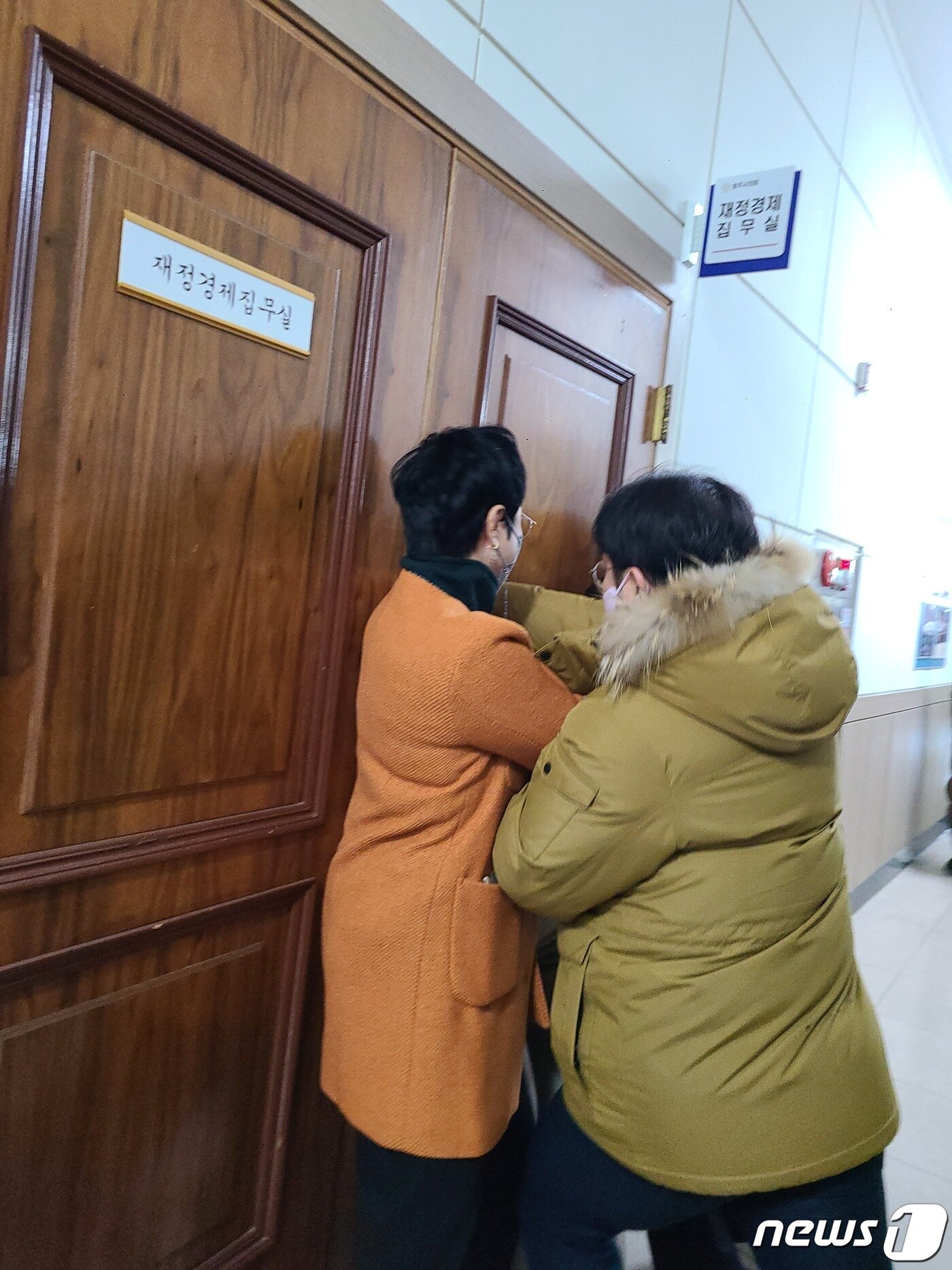 본문 이미지 - 충북 청주시청 본관동 철거에 반대하는 청주시의회 더불어민주당 의원들이 20일 4차 본회의에 참석하려는 같은 당 의원을 재정경제위원회 집무실에 데리고 간 뒤 설득하고 있다. 해당 의원이 집무실을 나오려 하자 민주당 의원들이 문을 막고 있다.2022.12.20/ⓒ 뉴스1 강준식 기자