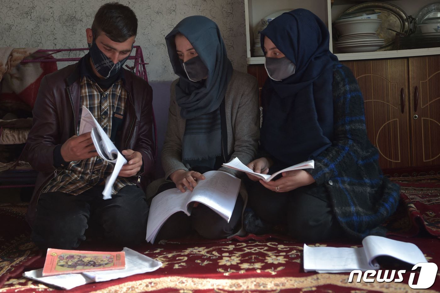 본문 이미지 - 지난해 12월 아프가니스탄 수도 카불의 한 가정집에서 히잡을 착용한 마르와&#40;가운데&#41;가 오빠인 하미드&#40;왼쪽&#41;에게 가정 교육을 받고 있다. 마르와는 불과 몇 달 전만 해도 이 가문에서 처음으로 대학에 들어간 여성이었지만 탈레반 당국에 의해 여성이란 이유로 대학 교육을 금지 받았다. 2022.12.23. ⓒ AFP=뉴스1 ⓒ News1 김성식 기자