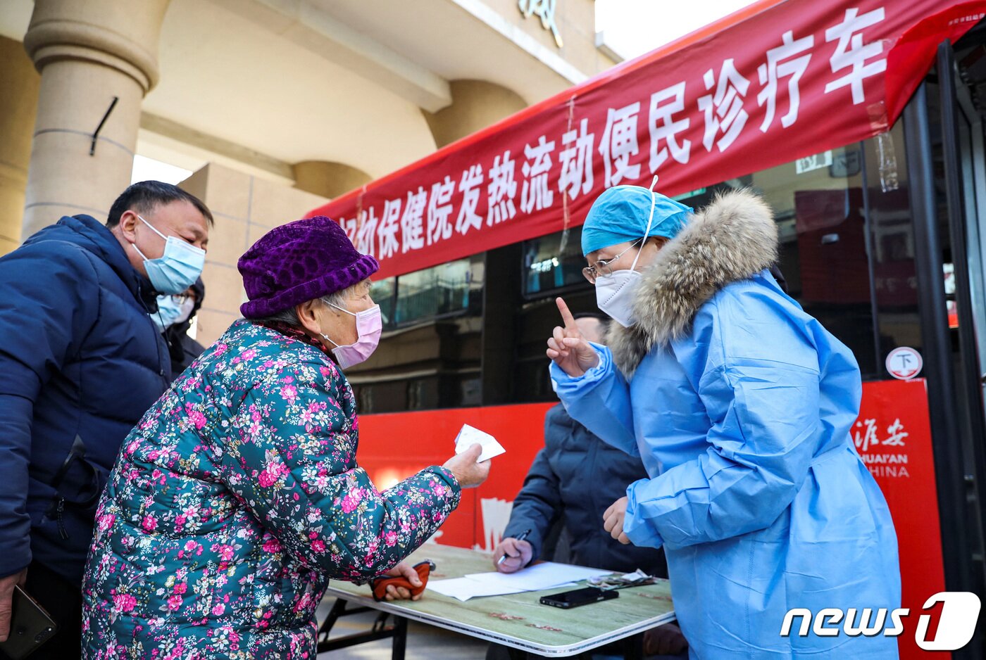 본문 이미지 - 중국 당국의 방역 완화 조치 이후 중국 전역에서 코로나19 확진자가 급증하는 가운데 25일 중국 장쑤성 화이안에서 방역복으로 중무장한 의료진이 버스를 개조한 이동식 발열 진료소를 찾은 시민들에게 유의 사항을 설명하고 있다. 2022.12.25. ⓒ 로이터=뉴스1 ⓒ News1 김성식 기자