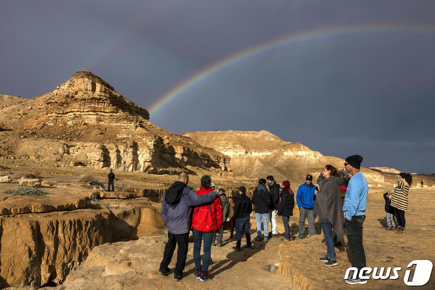 (디모나 AFP=뉴스1) 김성식 기자 = 26일(현지시간) 이스라엘 남부 도시 디모나의 네게브 사막에서 관광객들이 폭우가 그친 하늘 위로 뜬 무지개를 바라보고 있다. 2022.12 …