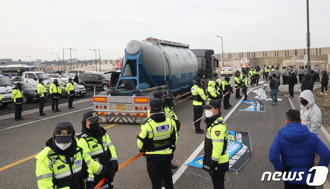 본문 이미지 - 화물연대 총파업 후 처음으로 제주지역에 시멘트가 반입된 8일 오전 제주시 애월항에서 벌크시멘트트레일러&#40;BCT&#41; 차량이 시멘트를 싣고 이동하는 동안 화물연대 노조원들과 경찰이 대치하고 있다. 2022.12.8/뉴스1 ⓒ News1 오현지 기자